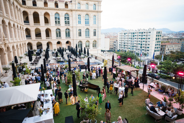 Vue plongeante sur la terrasse animée de l'InterContinental Marseille lors de la soirée d'entreprise, avec vue sur la cité phocéenne.