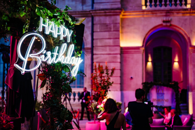 Enseigne lumineuse au néon "Happy Birthday" intégrée dans un décor végétal sous un éclairage rose, lors de l'événement corporate marseillais.