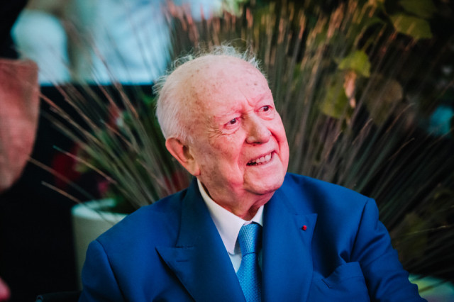 Portrait sur le vif d'un invité d'honneur souriant en costume bleu lors de la célébration en région PACA. Photo signée Gilles Perbal.