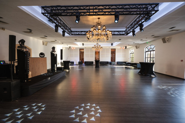 Salle de réception vide avec parquet et lustre, préparée pour la soirée d'entreprise événementiel Higco au Château de Saint Hilaire.