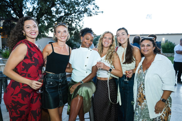 Groupe de collaboratrices souriantes posant pendant le cocktail en extérieur au Château de Saint Hilaire.