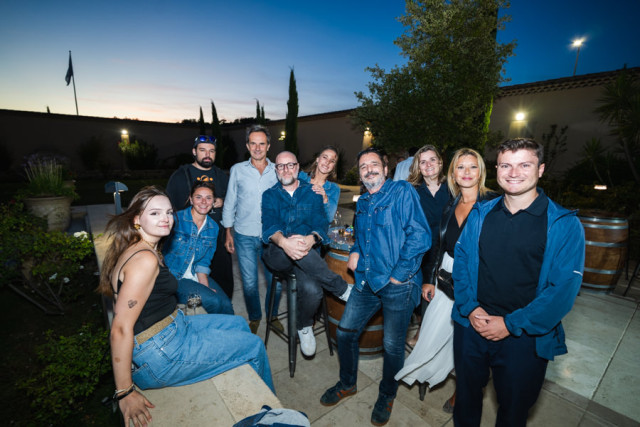 Équipe de collaborateurs posant de manière détendue, assis sur un muret lors de la soirée d'entreprise.