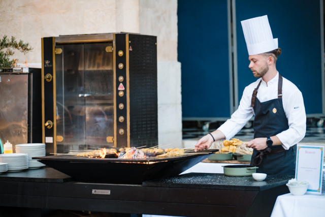 Chef préparant des mets à la plancha lors d'une animation culinaire pour une soirée d'entreprise à Marseille.