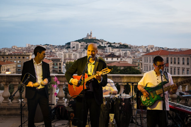 Chanteur et guitariste d'un groupe de musique live animant la soirée de rentrée corporate avec vue sur la ville.