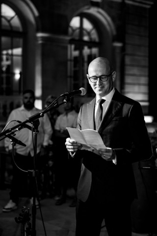 Photographie en noir et blanc d'un dirigeant prononçant son discours de rentrée devant les collaborateurs.