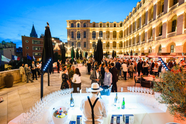 Barman de dos préparant des verres derrière un comptoir lumineux face aux invités de l'événement BtoB
