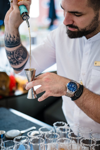 Gros plan sur les mains d'un mixologue professionnel versant une dose d'alcool pour un cocktail sur-mesure.