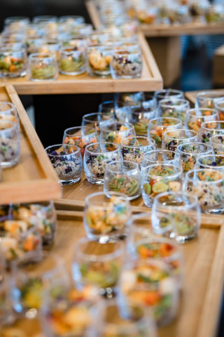 Disposition géométrique de verrines apéritives colorées sur le buffet du traiteur pour le cocktail dînatoire.